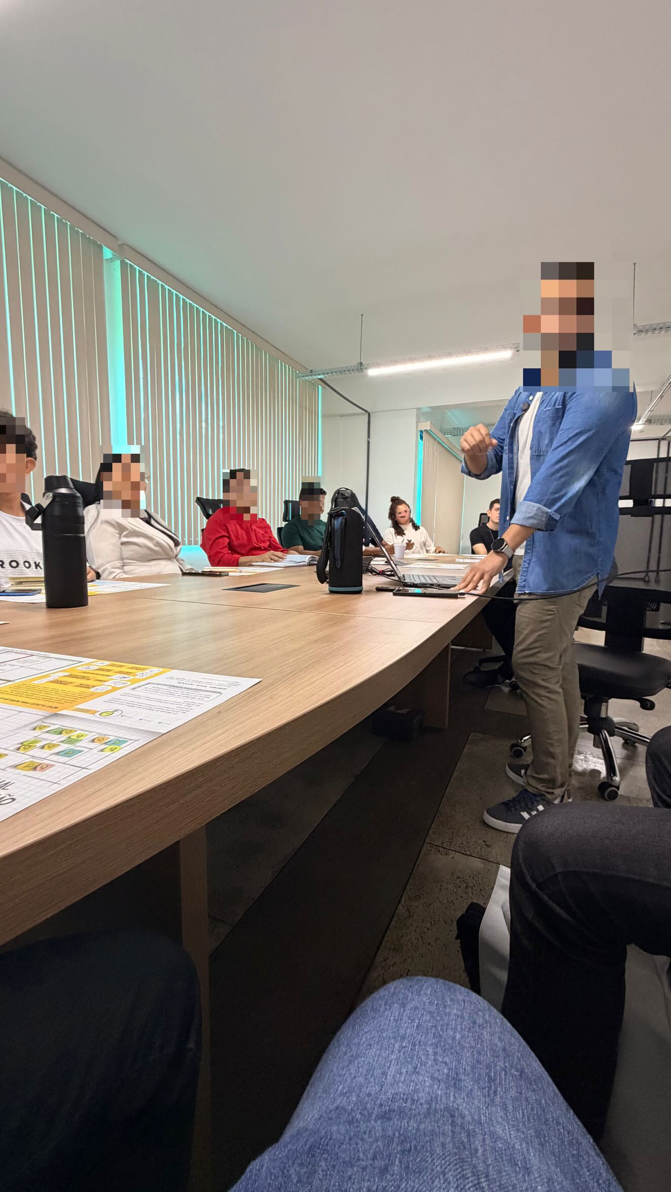 Vítor Magalhães apresentando ideias a um grupo, junto ao notebook em uma mesa de reunião